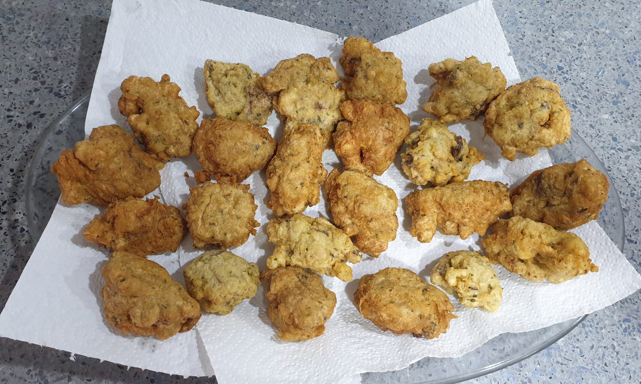 Buñuelos dorados escurriendo sobre papel de cocina absorbente